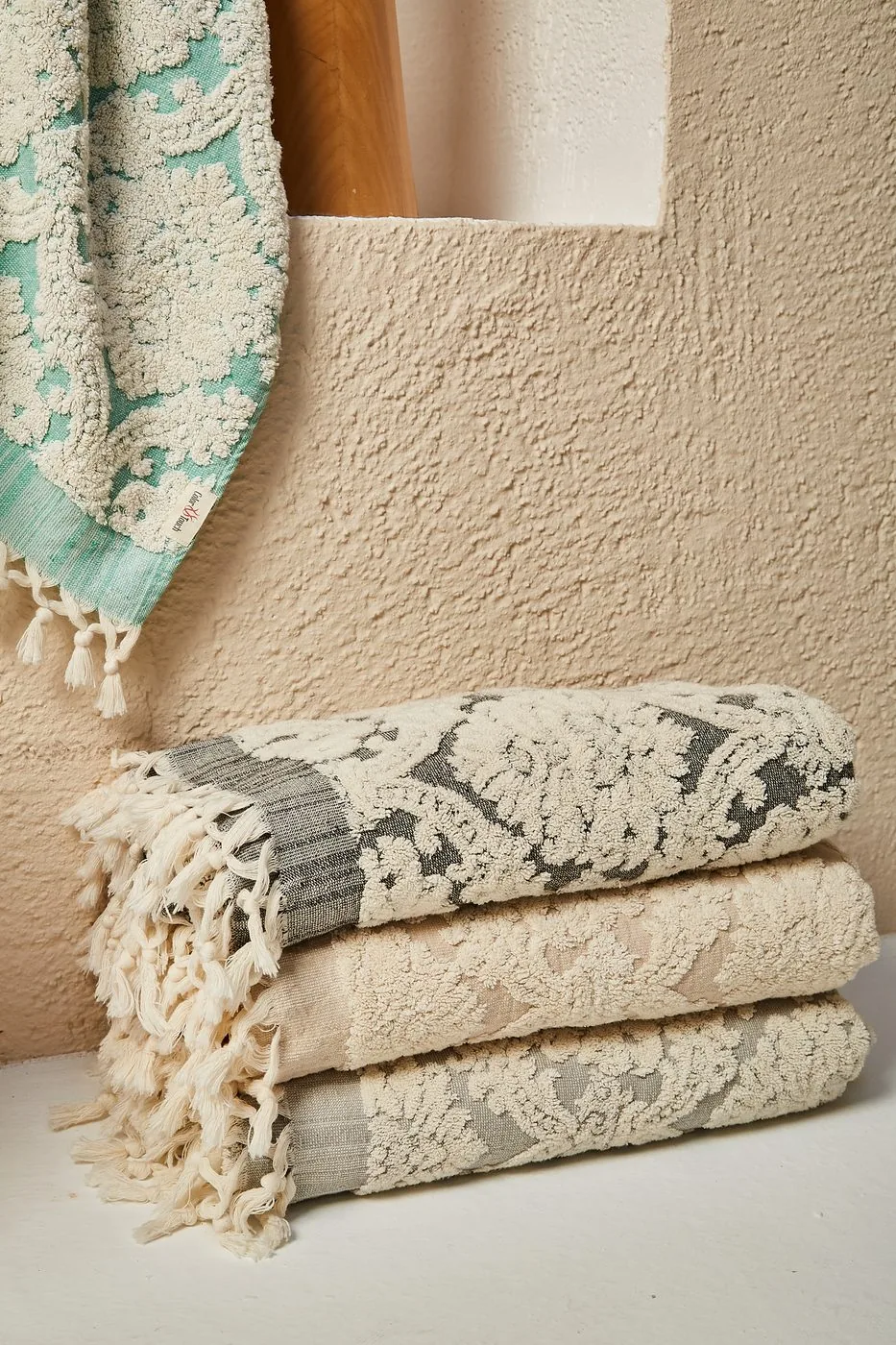 Damask bath towels in mint, charcoal and beige, folded and rolled