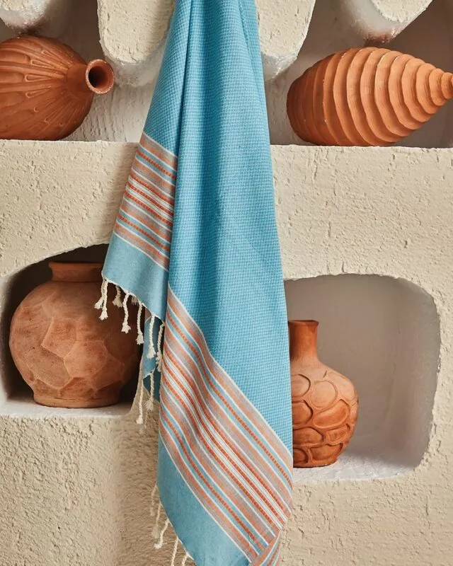 Afrodit cotton peshtemal in turquoise with orange stripes, hanging in a plaster niche